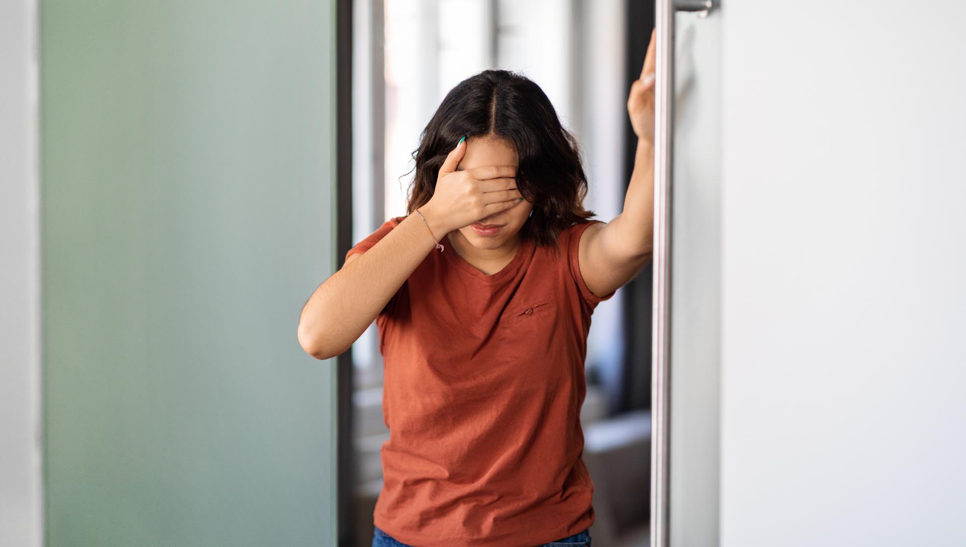 女性因頭暈而扶著門框，出現眩暈與平衡不適的情境示意