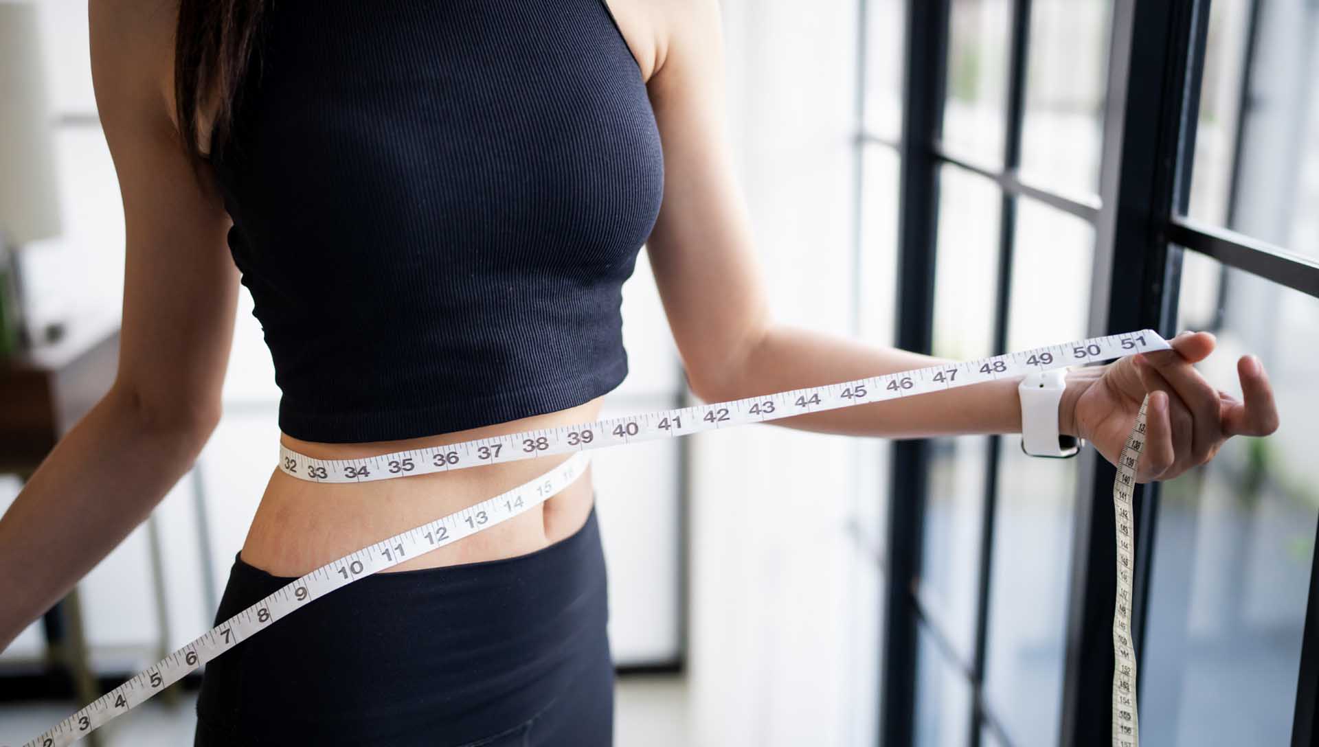 女性使用皮尺測量腰圍，呈現健康體重與生活管理的情境